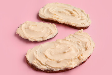 Tasty sandwiches with cream cheese on pink background