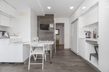Large kitchen equipped with glossy white cabinets