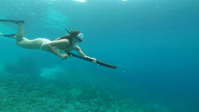 Swimming, spear and woman in ocean for fishing, hunting and catch fish on adventure, holiday and vacation. Diving, travel and female person in tropical water with harpoon snorkeling for spearfishing
