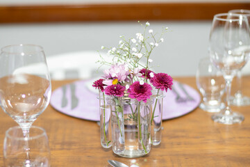 Mesa elegante com pratos decorados, rosas, flores, copos e taças de cristal