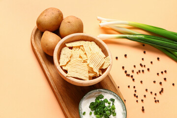 Fototapeta na wymiar Bowl of tasty sour cream with sliced green onion and potato chips on orange background