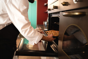 close-up shot. chef's hands put a baking sheet with chicken fillet for making sandwiches in the oven
