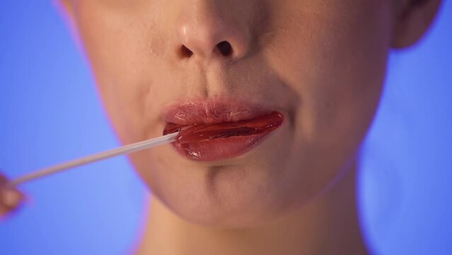 Młoda kobieta lize lizak w kształcie serca