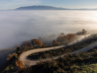 Aerial drone view of a curcy road above a sea of fog - 610758447