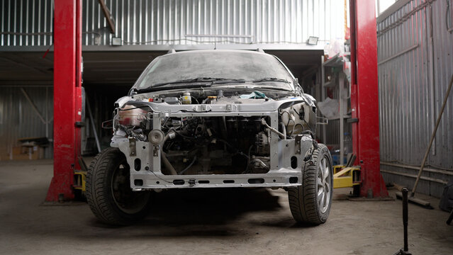 The frame of a powerful white car with body parts removed. Car bumper repair and painting. Disassembled car, in a car repair shop.