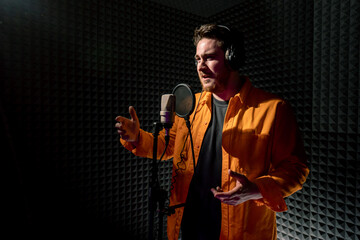 young pop rap artist emotionally recording new song in professional recording studio singing with...