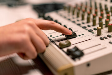 professional recording studio sound engineer with finger adjusts volume level on mixing console...