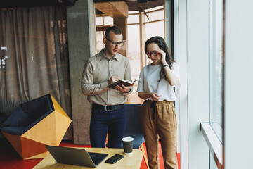 Young male and female colleagues work in a spacious office. Successful people are working on a new...