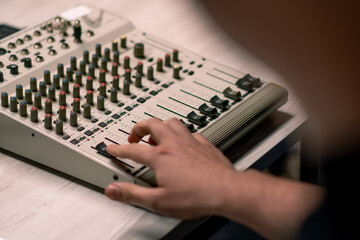 professional recording studio sound engineer with finger adjusts volume level on mixing console...