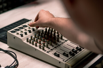 professional recording studio sound engineer with finger adjusts volume level on mixing console...
