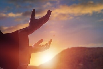 Silhouette of hands praying on sky background