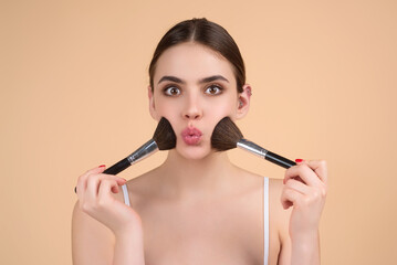 Girl hold blush blusher apply powder visage isolated over studio background. Woman powdering...