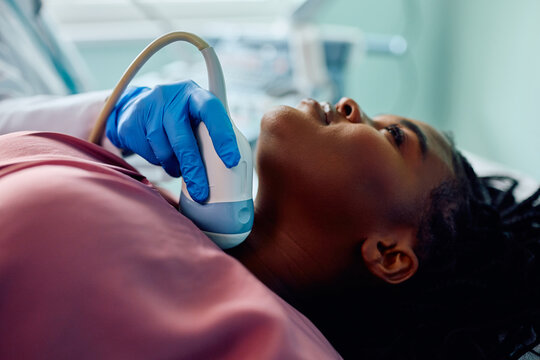 Black female patient during ultrasound thyroid gland examination at clinic.