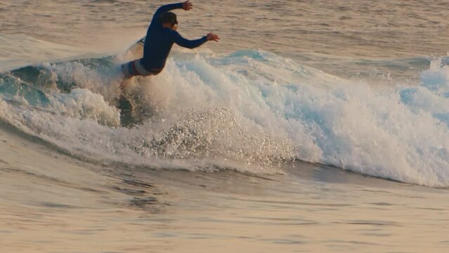 Male surfer rides the wave in the ocean and does sharp turn