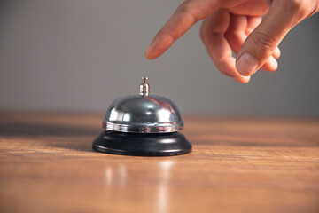 Service bell locating at wooden table touching finger