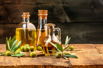 olives berries in wood bowls and oil in glass bottles on a wooden background. Healthy and detox food concept