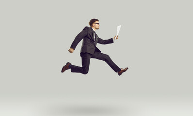 Fototapeta na wymiar Successful Caucasian man company entrepreneur or manager in air reads paper documents in pose of running businessman symbolizing speed of corporation development posing on studio background
