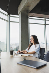 Modern office woman worker in casual clothes works on a laptop. Female manager at workplace working on new project using laptop. modern workspace