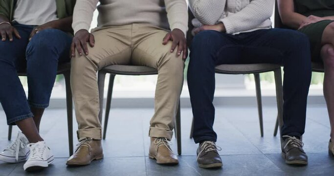 Business people, hands and legs in waiting room row for workshop, seminar or meeting presentation at office. Group of employees sitting in line during training, interview or recruiting at workplace