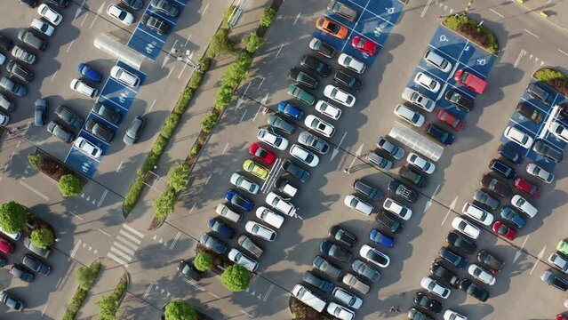 Aerial drone flight parking near big shopping mall in city, car traffic, parking overhead drone top down view, daylight, summer evening sunny weather, lot of cars, busy supermarket car park