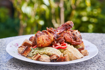 Barbeque chicken drum sticks, spicy and sweet asian style on lettuce salad and bread crumbs, served outside on the rustic style plate and granit stone table in garden restaurant. Healthy balanced dish