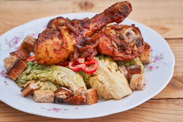 Close up picture of the marinated and roasted chicken drum sticks on the top of vegetable salad made from lettuce and paprika with bread crumbs. Balanced light dish, full of nutritions and vitamins.