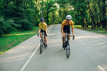 Couple riding bicycles outside of the city and wearing helmets and sunglasses