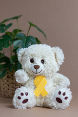 Toy bear with a yellow ribbon on a nude background.