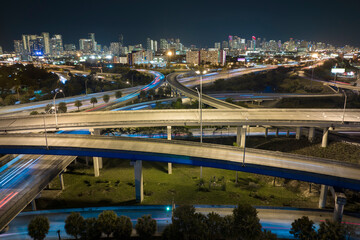 Aerial view of american freeway intersection at night with fast driving cars and trucks in Miami, Florida. View from above of USA transportation infrastructure
