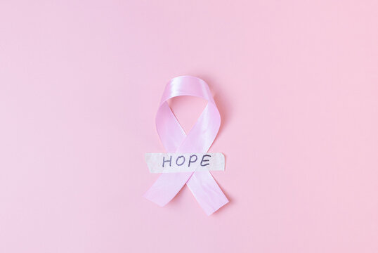 Pink ribbon with sticky tape and the word: hope on a pink background.
