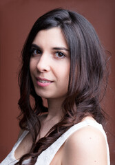 Obraz premium Pale-skinned Mediterranean woman smiles on brown backdrop