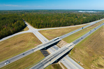 Aerial view of freeway overpass junction with fast moving traffic cars and trucks in american rural...