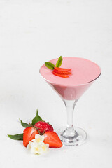 Italian dessert. Strawberry cream Panna Cotta, decorated with fresh strawberry slices, in a martini glass. White background. Copy space