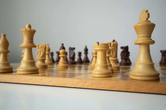 Focus on the white chess rook tower. Angled photo of the board with pieces in perspective