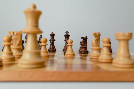 Focus on the black and white king of chess. Angled photo of the board with pieces in perspective