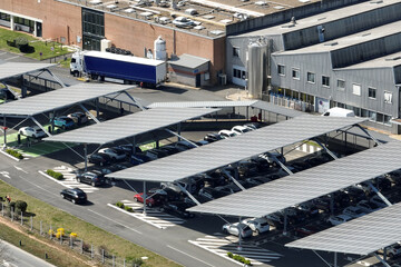 Aerial view of solar panels installed over parking lot with parked cars for effective generation of...
