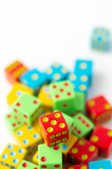 Pile of Multi-Colored Dice on a White Background; Red Dice with Five Pips on Top in Focus