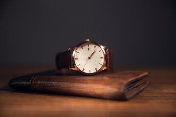 brown watch in brown wallet on the wooden table