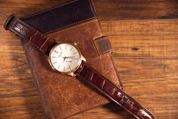 brown watch in brown wallet on the wooden table