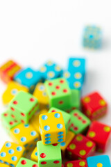 Pile of Multi-Colored Dice on a White Background; Yellow Dice with Four Pips on Top in Focus