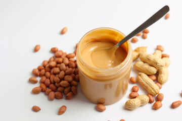 Fototapeta premium peanut butter and raw peanuts on a light background