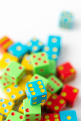Pile of Multi-Colored Dice on a White Background; Blue Dice with Six Pips on Top in Focus