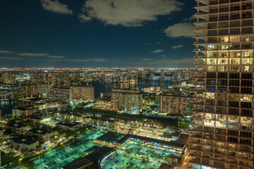 High angle view of brightly illuminated residential high-rise building at night in Sunny Isles Beach city in Florida, USA. Housing development in modern american urban area
