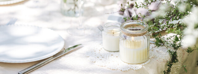 Rustic zero waste wedding decor with natural elements. Fresh spring blooming flowers, candles, linen napkins, wine glasses. Eco friendly decoration for special holiday dinner. Romantic place banner