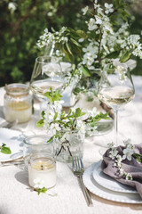 Romantic elegant luxury wedding table decor with white fresh spring blooming cherry apple tree flowers. Glass, candles, floral decoration for special marriage holiday event. No plastic zero waste