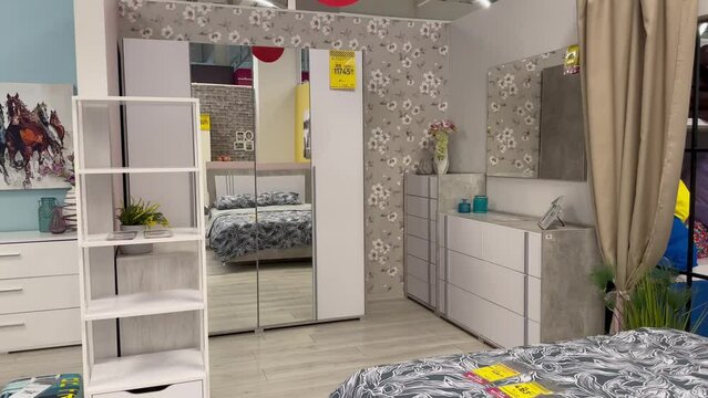Modern furniture for the bedroom of a house in the furniture department of a large shopping center, cabinets, bedside tables, a mirror, a bed in a furniture salon, bedroom decor