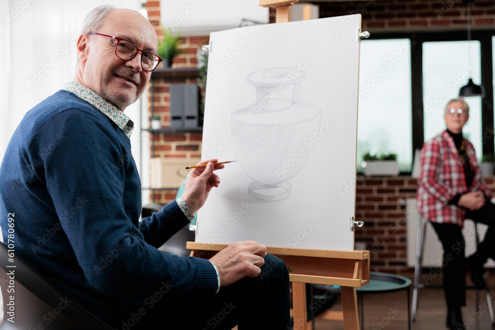 Poster happy senior man attending art workshop. positive retired student sitting at easel and practicing dr