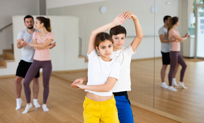 Portrait of smiling girl with boy performing pair dance movements, family practicing dance in pair