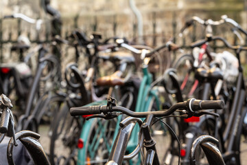 Fototapeta na wymiar Selective blur on the handlebar of bicycles, parked in a bicycle parking, in Maastricht city center. Cycling and bikes are a symbol of netherlands.