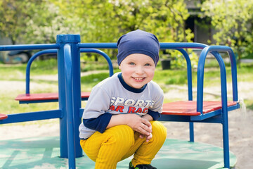 A little boy is sitting on a merry-go-round. Child on the playground